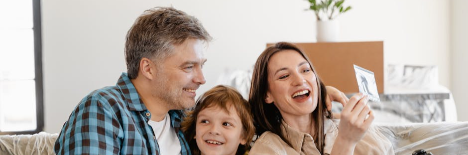 A cheerful family enjoys time together on a couch surrounded by moving boxes in their new home.
